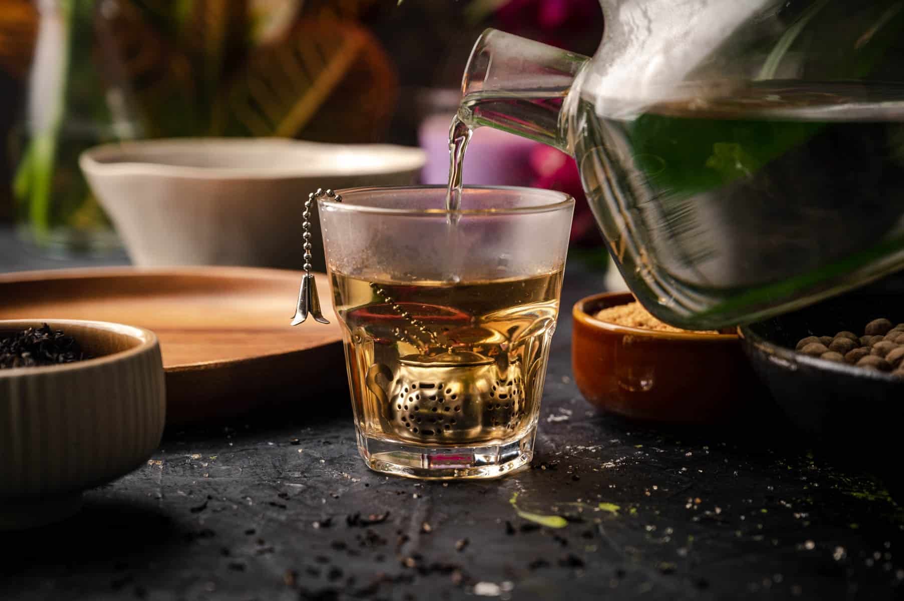 Pouring hot water over tea in a glass cup.
