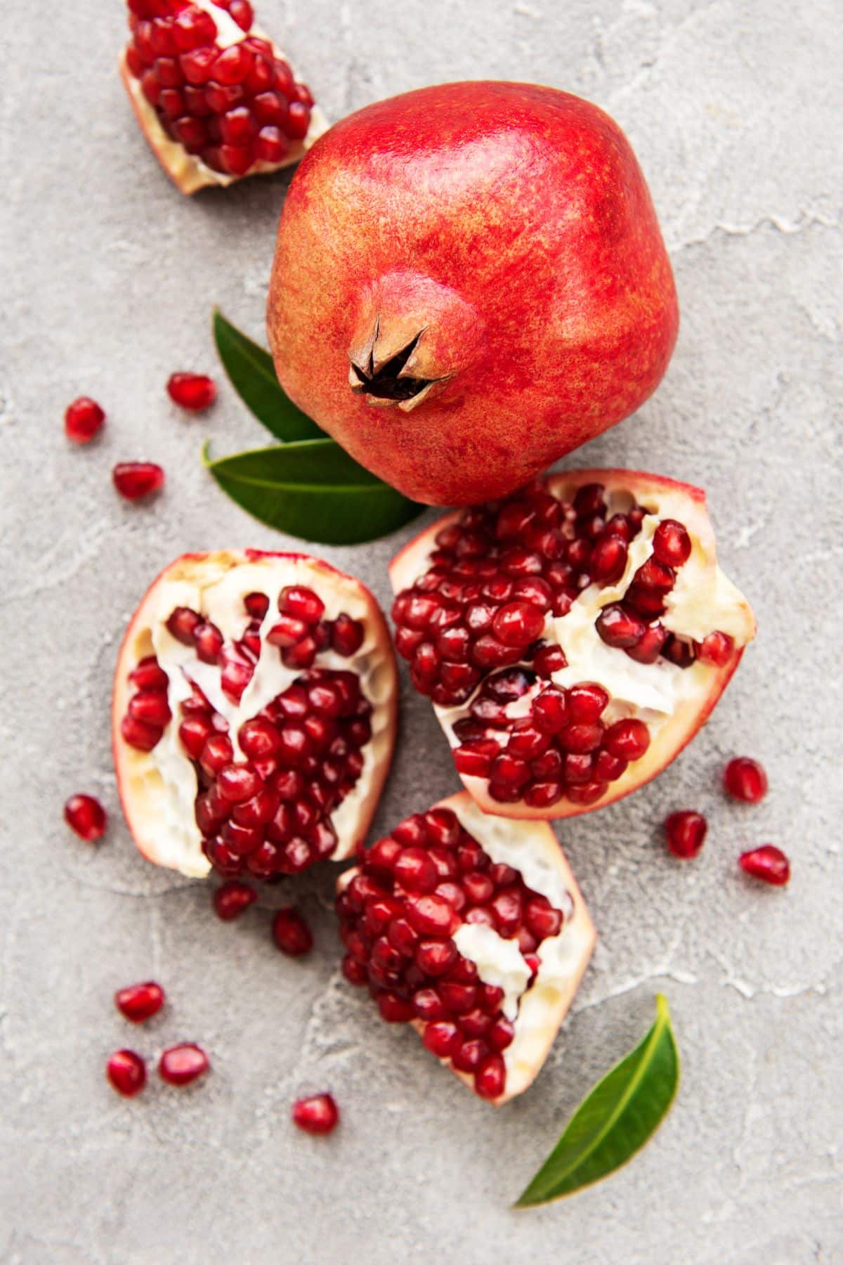 Pomegranate on a gray background with leaves.