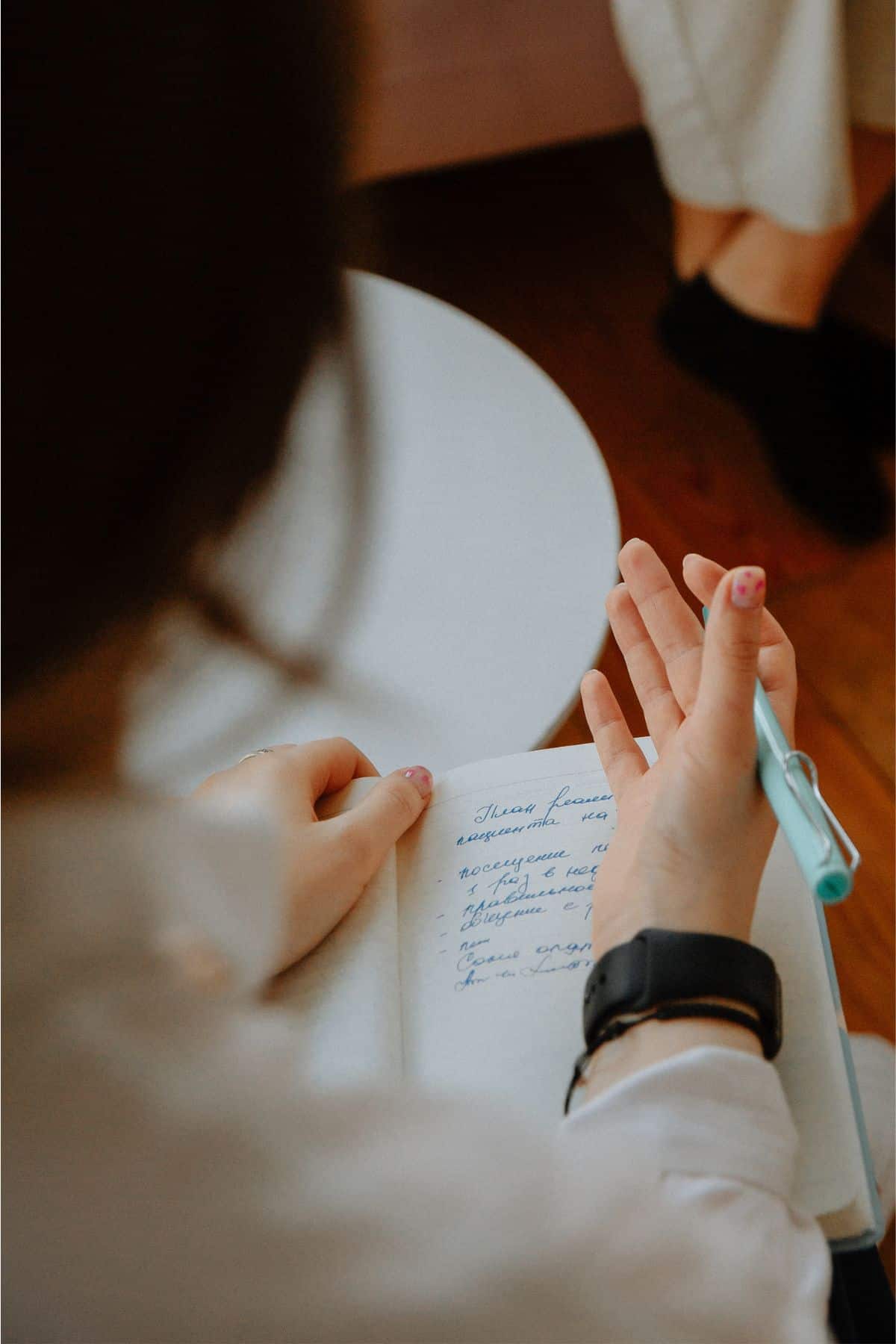 A woman writing in a notebook with a pen.