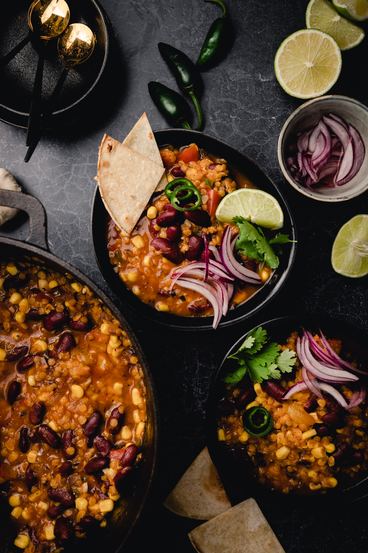 A bowl of homemade vegan chili with tortillas and limes.