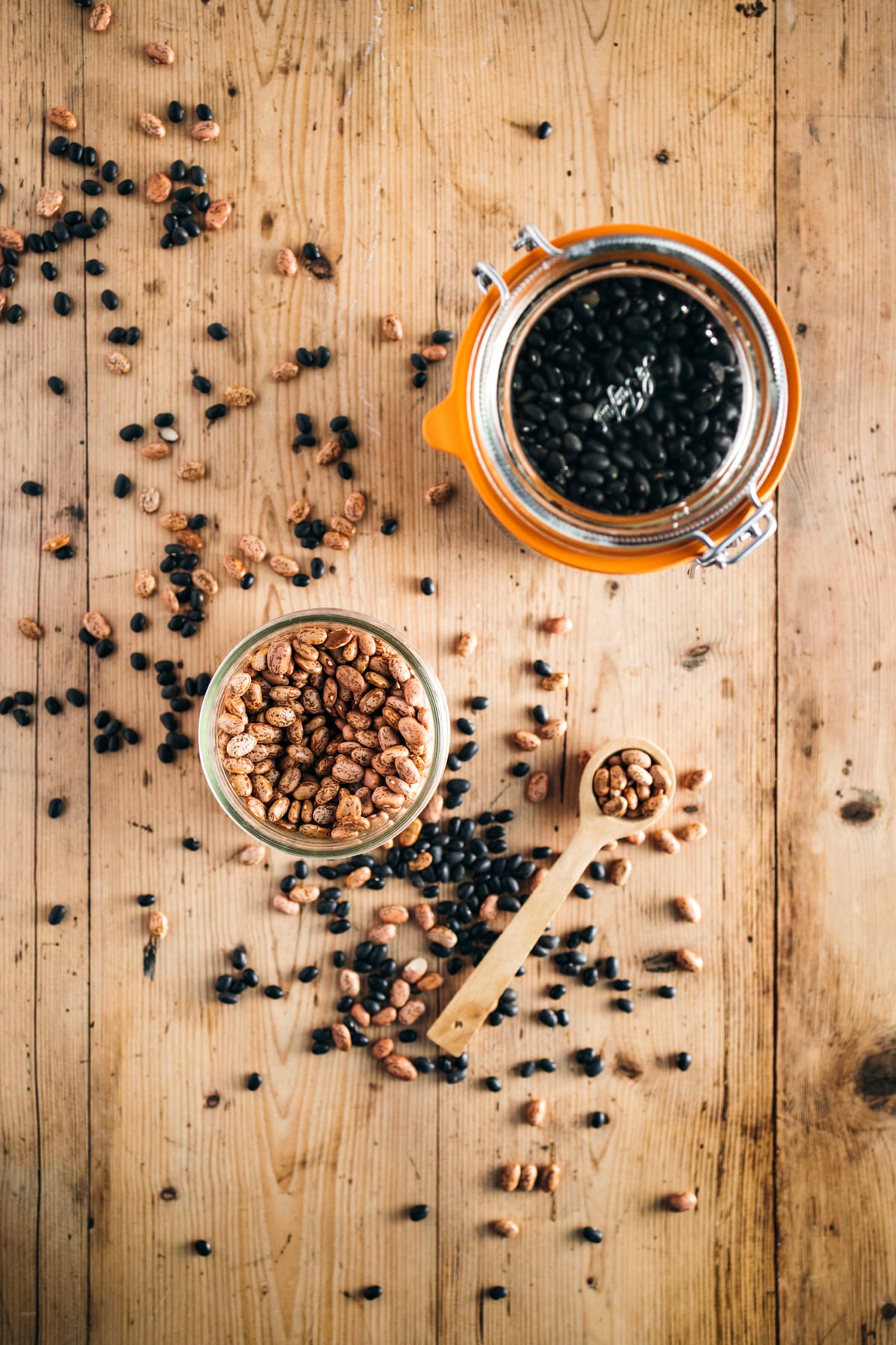 Black beans in a jar and a spoon on a wooden table.