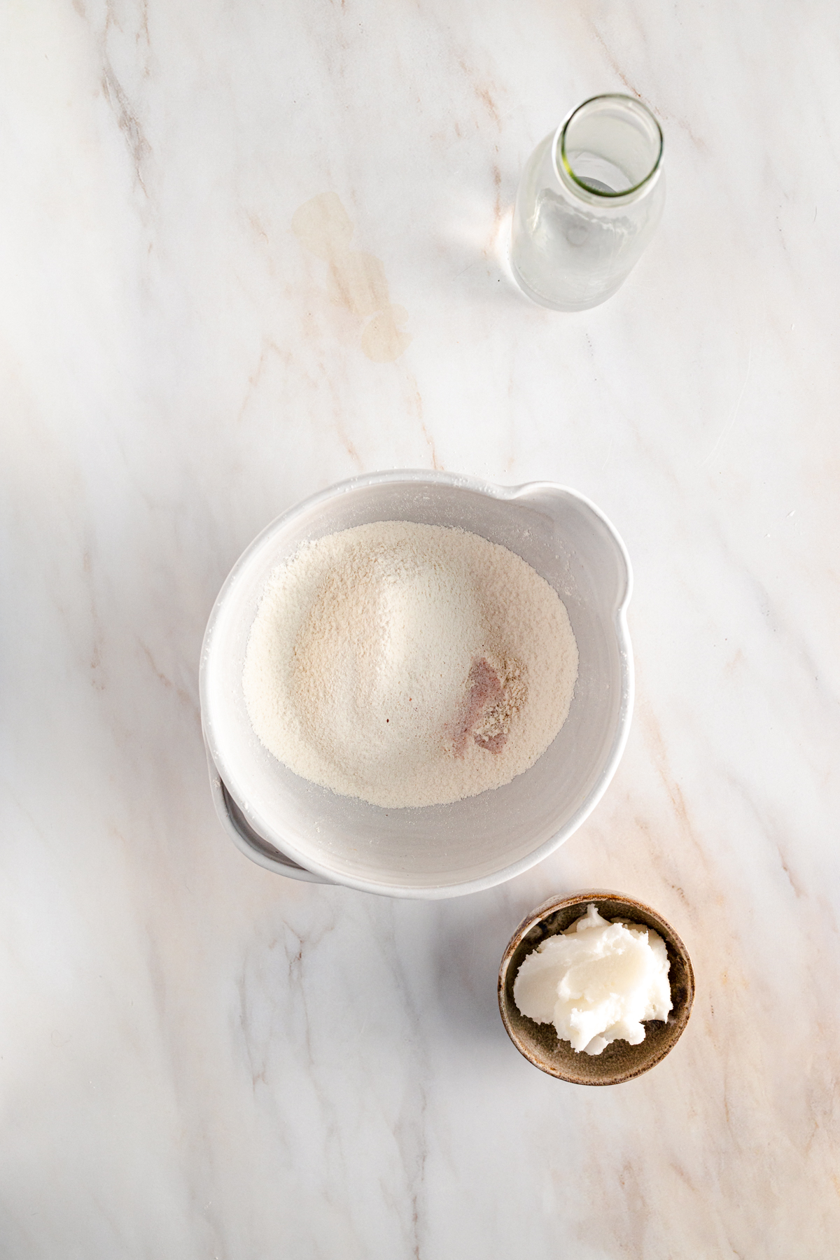 A bowl of sugar and a glass of water on a marble table.