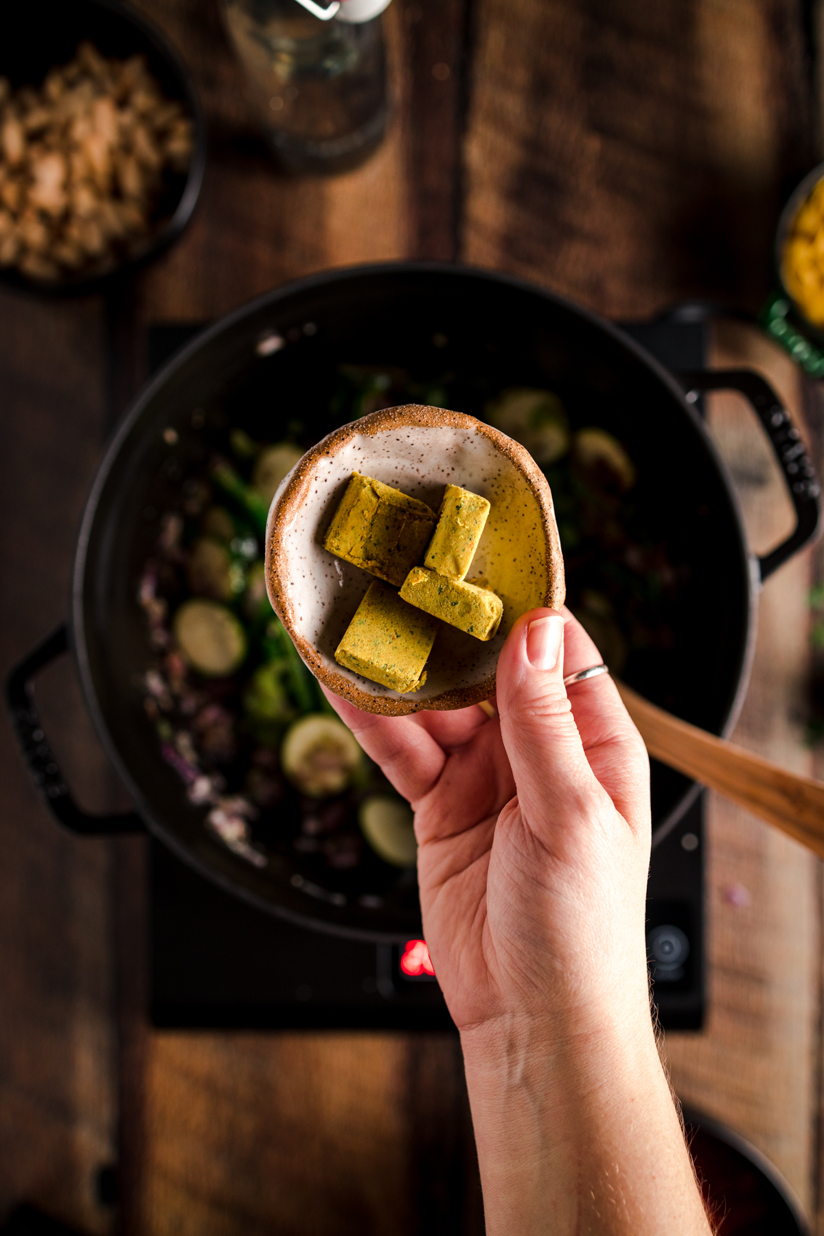 A person holding a spoonful of food in a pan.