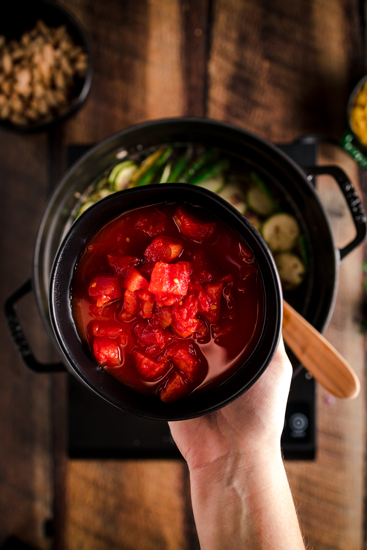 A person holding a bowl of soup on a wooden table.