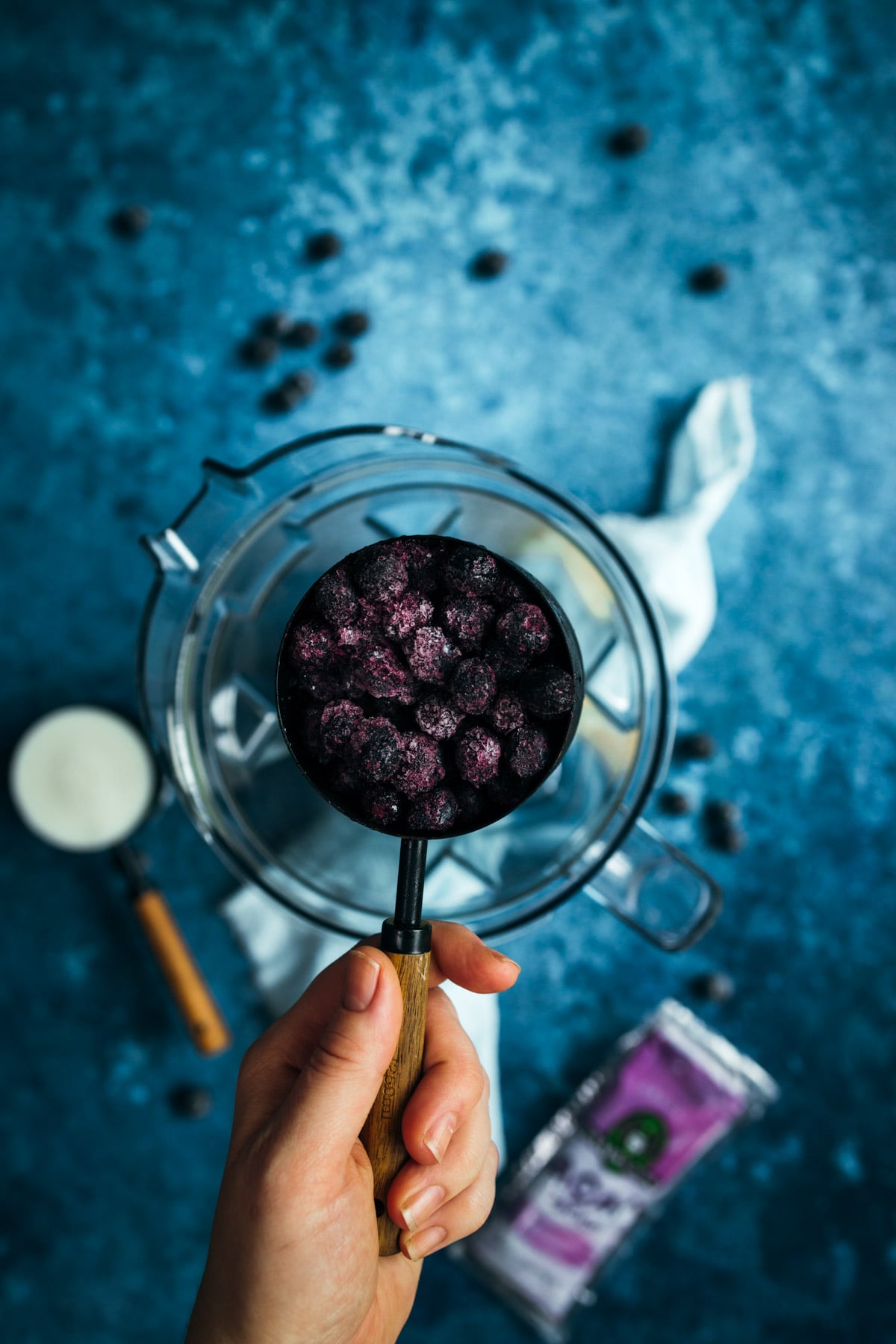 A person holding a measuring cup of blueberries.