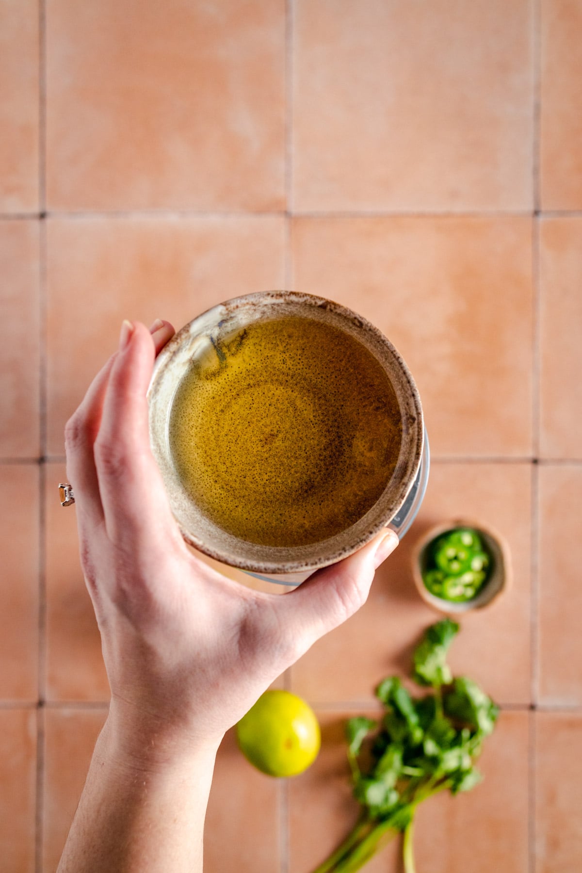 A hand holding a bowl of green tea.