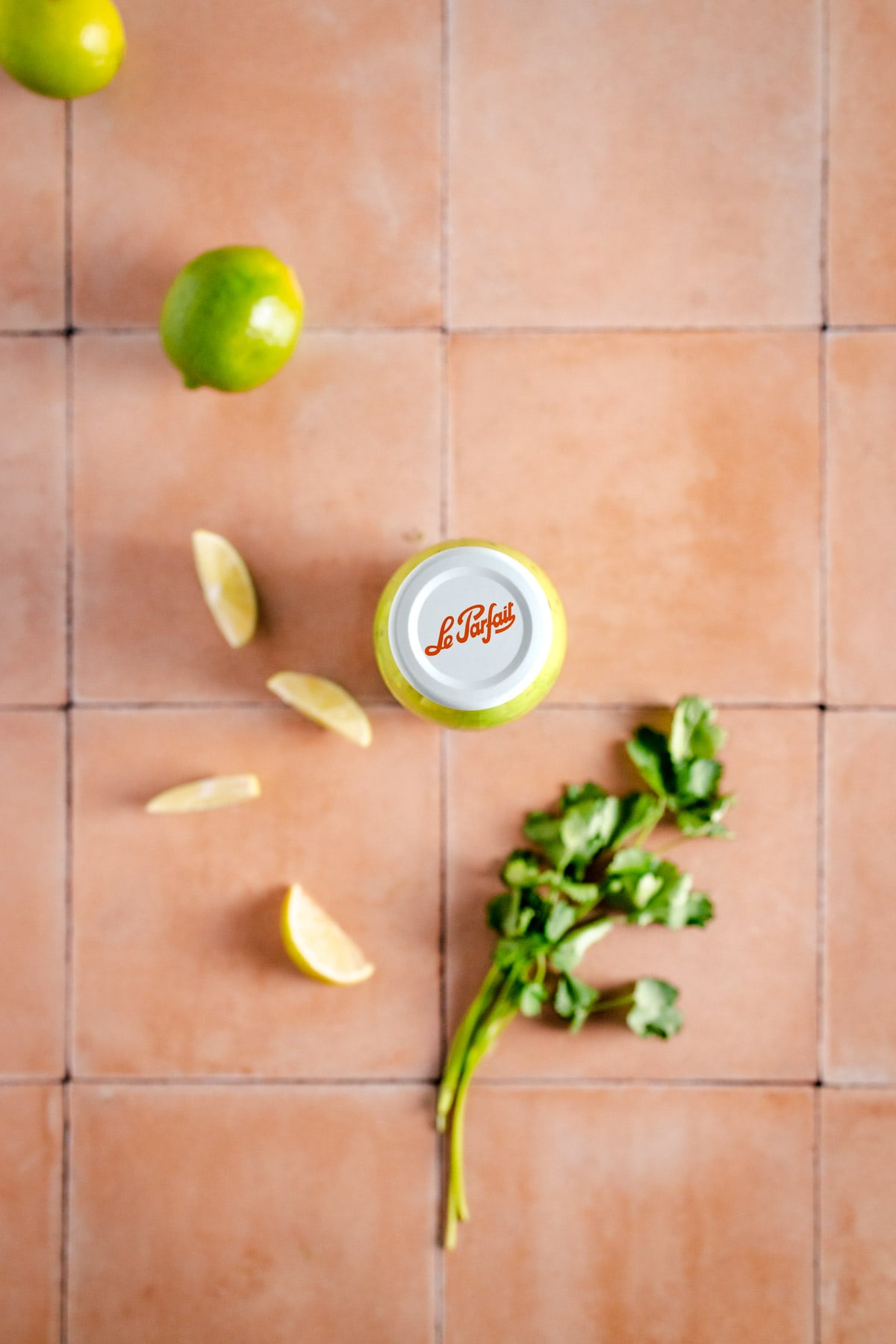 A bottle of lime juice on a tiled floor.