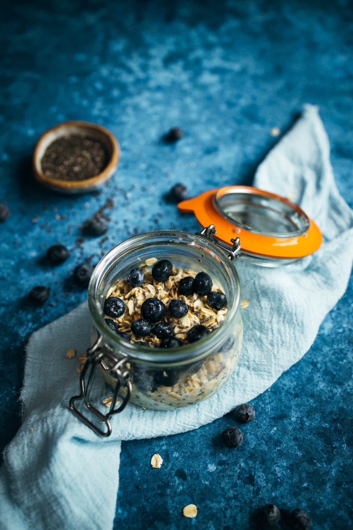 Blueberry oats in a glass jar on a blue background.