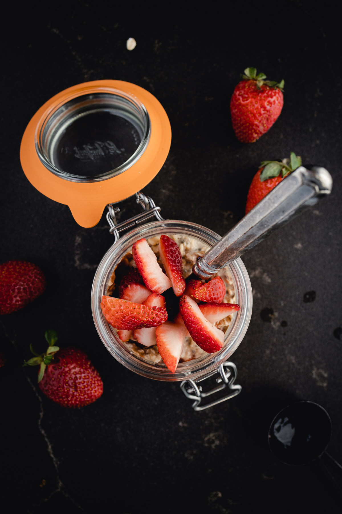 A bowl of oats with strawberries and a spoon.