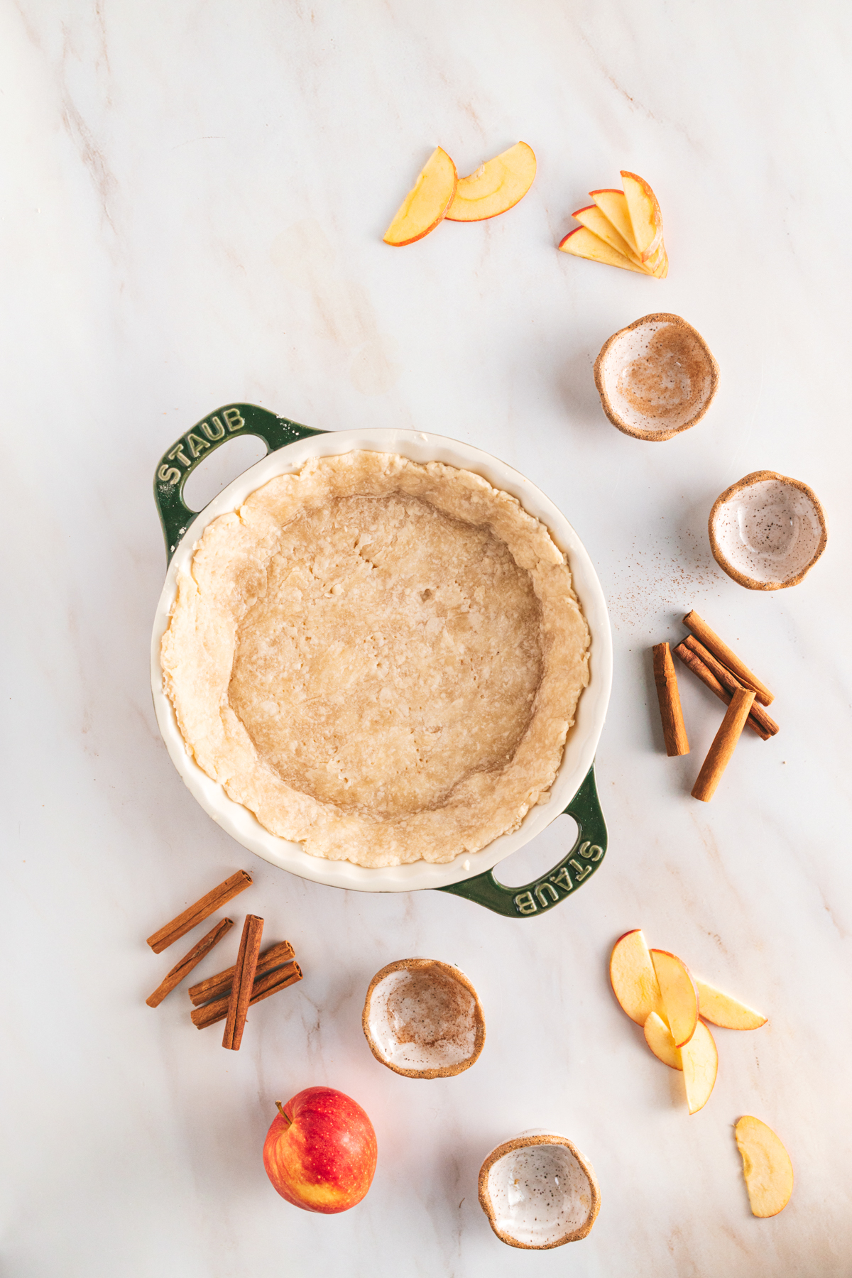 A pie with apples and cinnamon on a marble table.