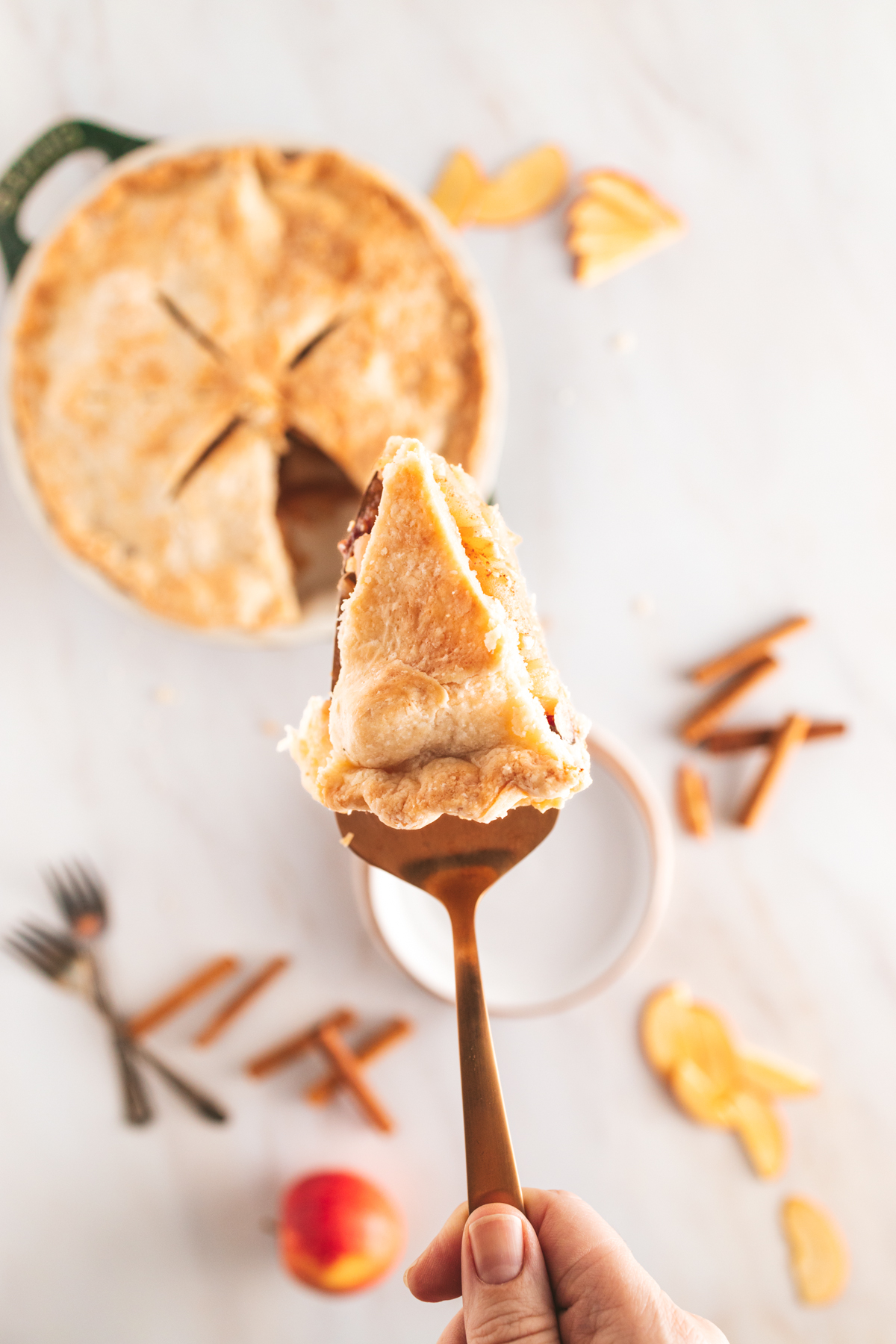 A person holding a piece of apple pie on a fork.