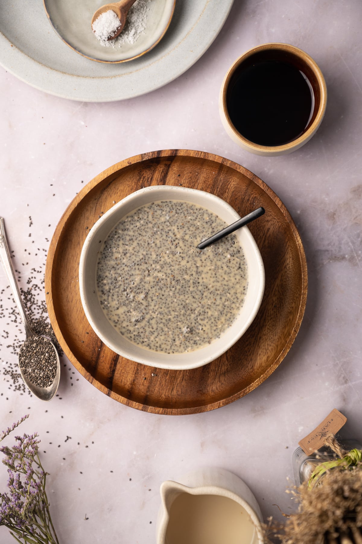A bowl of chia seeds and a spoon on a plate.