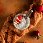 A glass of pudding with strawberries on top.