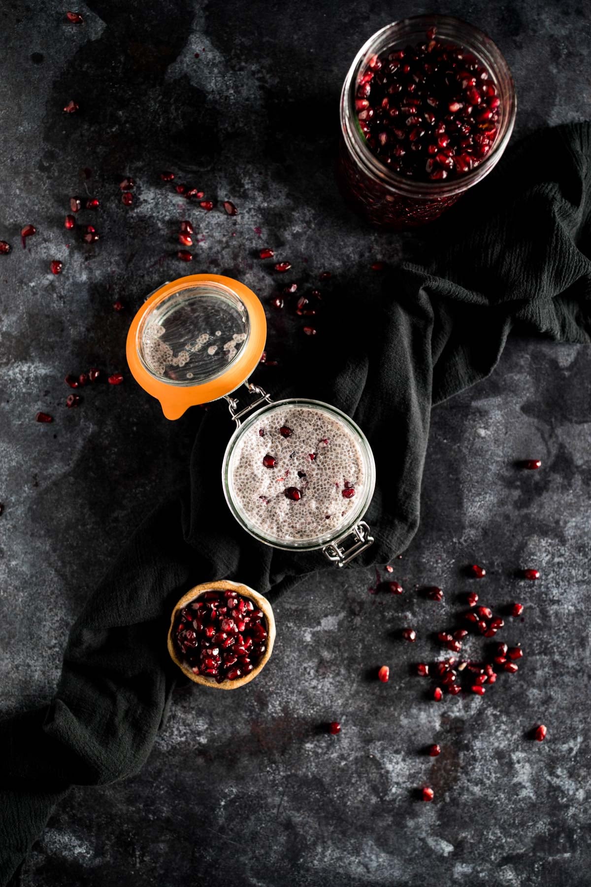 A bowl of pomegranate seeds on a black background.