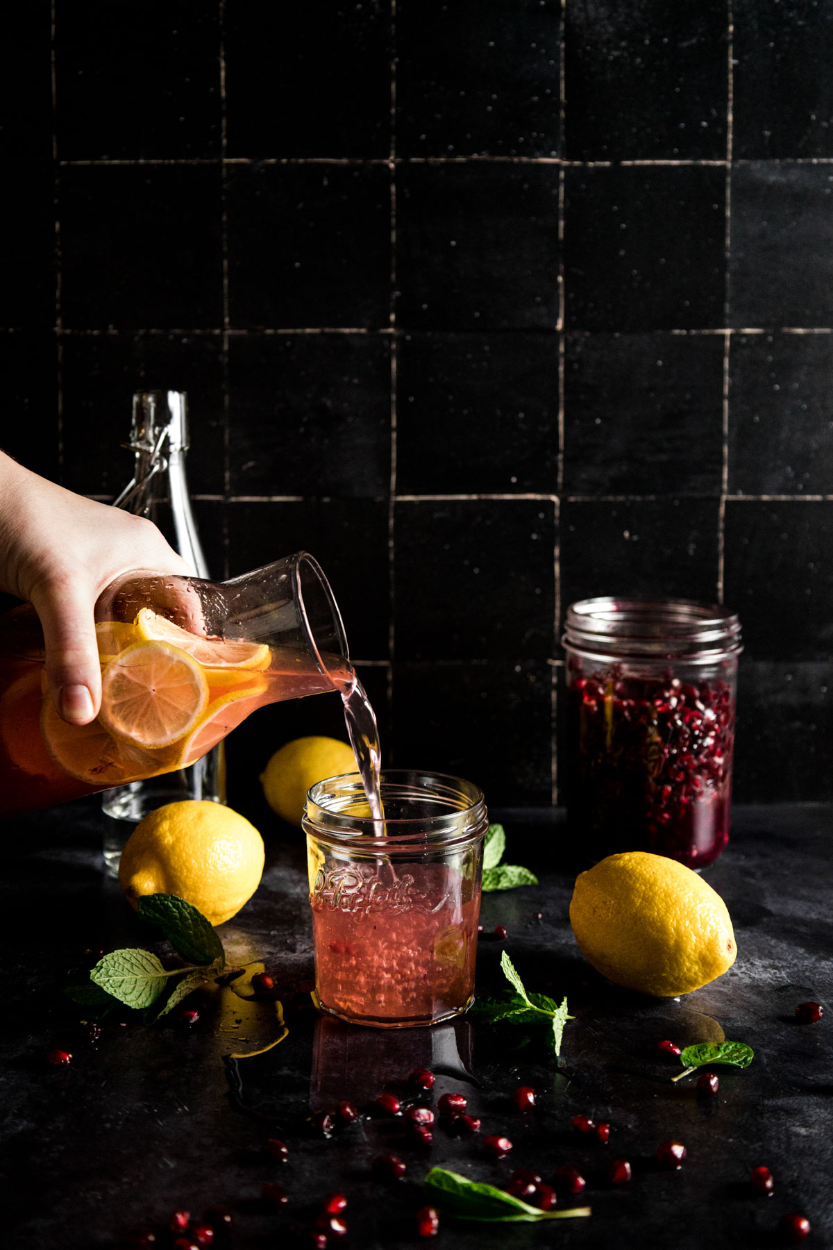 A person pouring pomegranate juice into a jar.