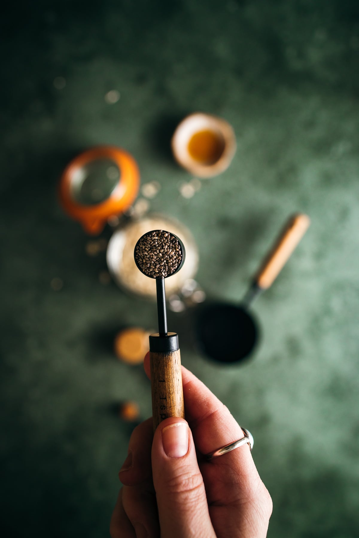 Hand holding a portafilter with freshly ground coffee on a blurred background with coffee-making tools.