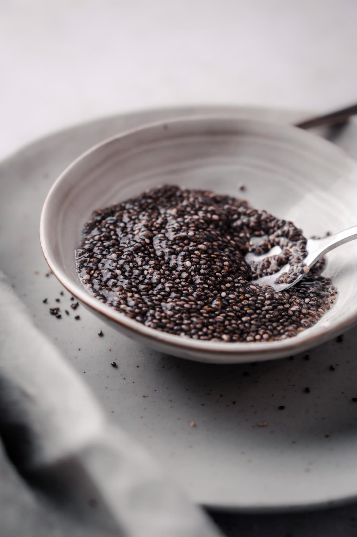 A close-up of a bowl filled with wet chia seeds, with a spoon partially submerged in the seeds.