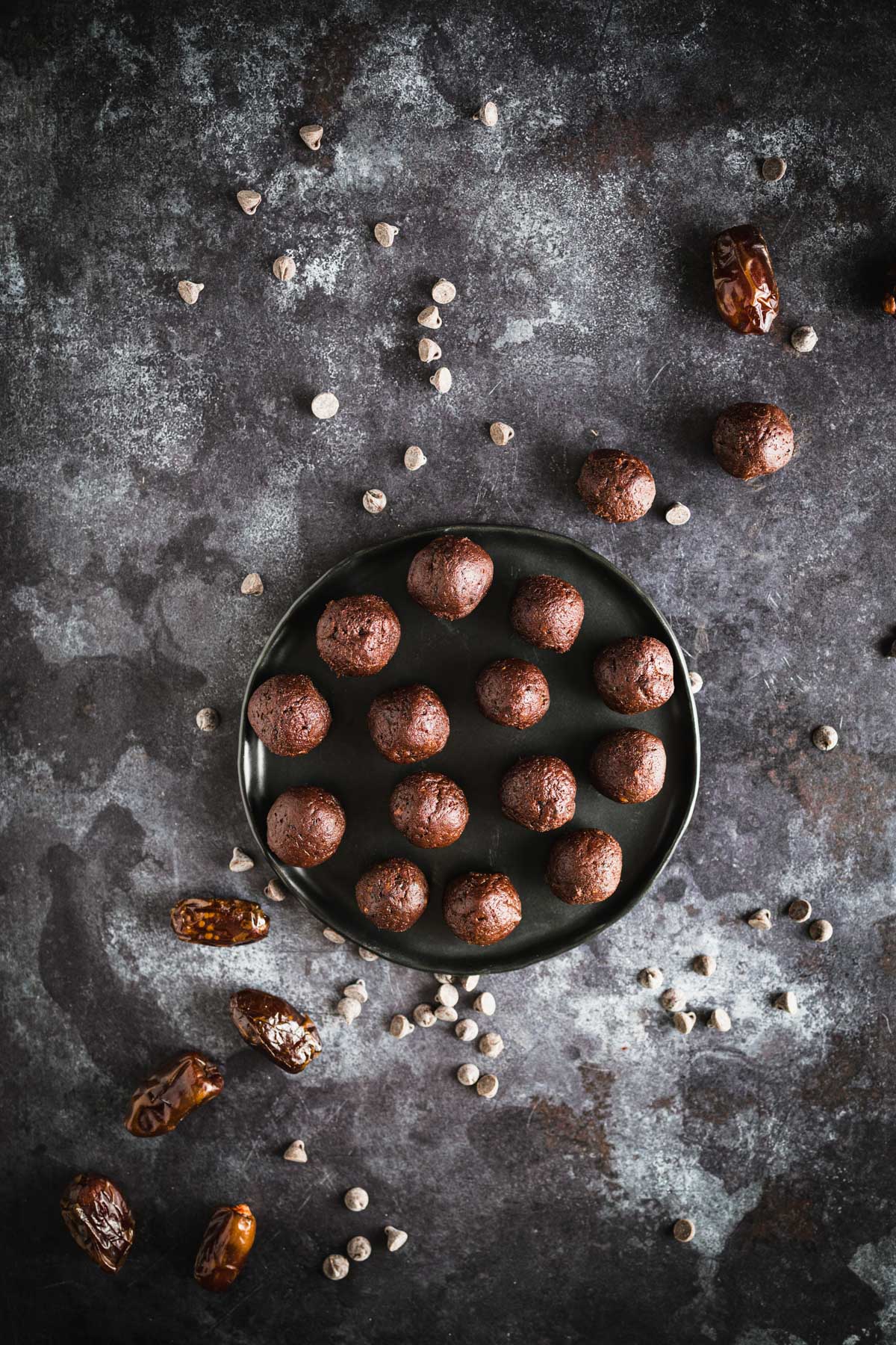 Homemade chocolate date balls on a black plate.