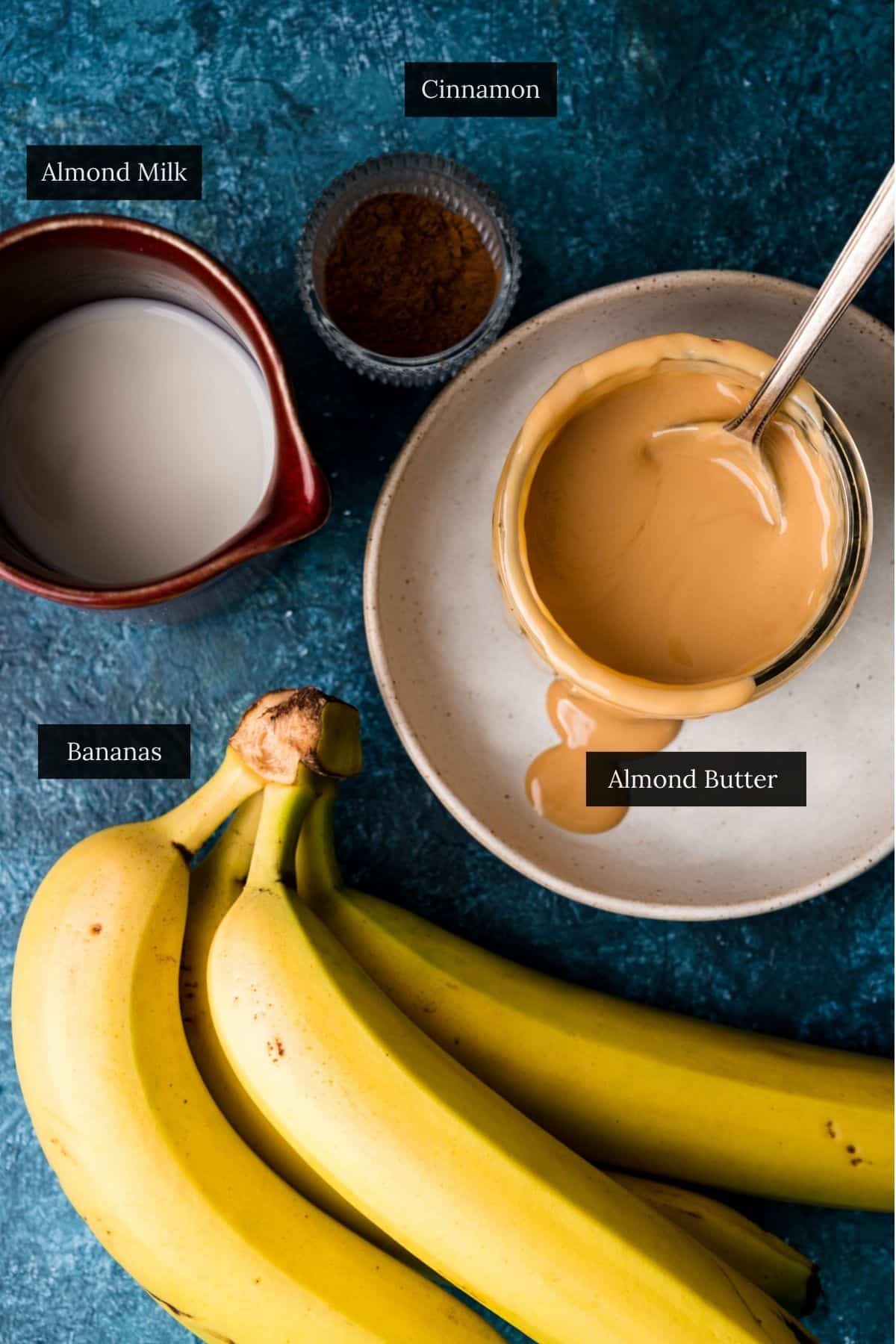 Ingredients for a almond butter smoothie on a blue surface.