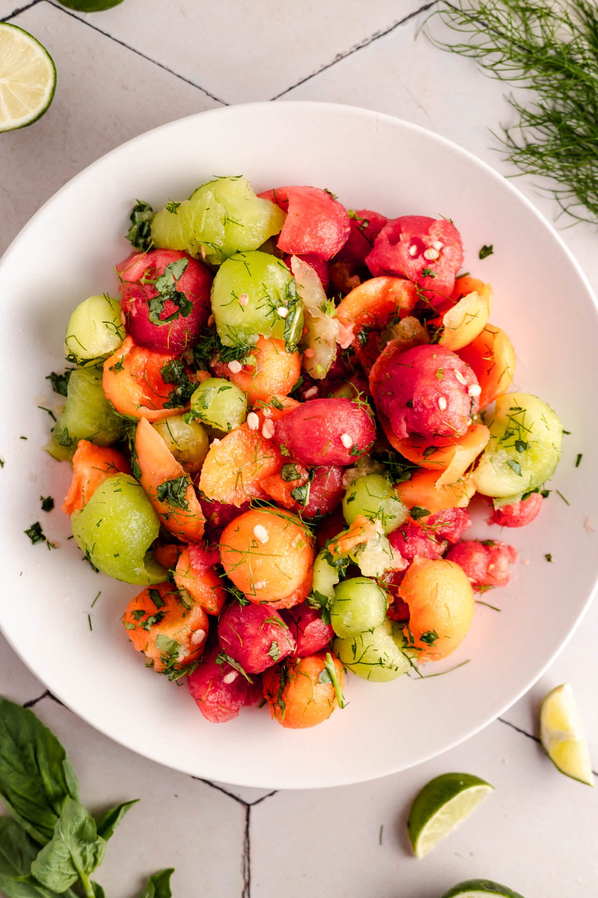 A white plate with a colorful melon ball salad.