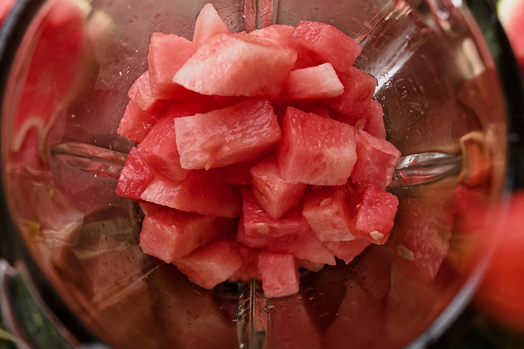 Close-up of a blender filled with chopped watermelon pieces.