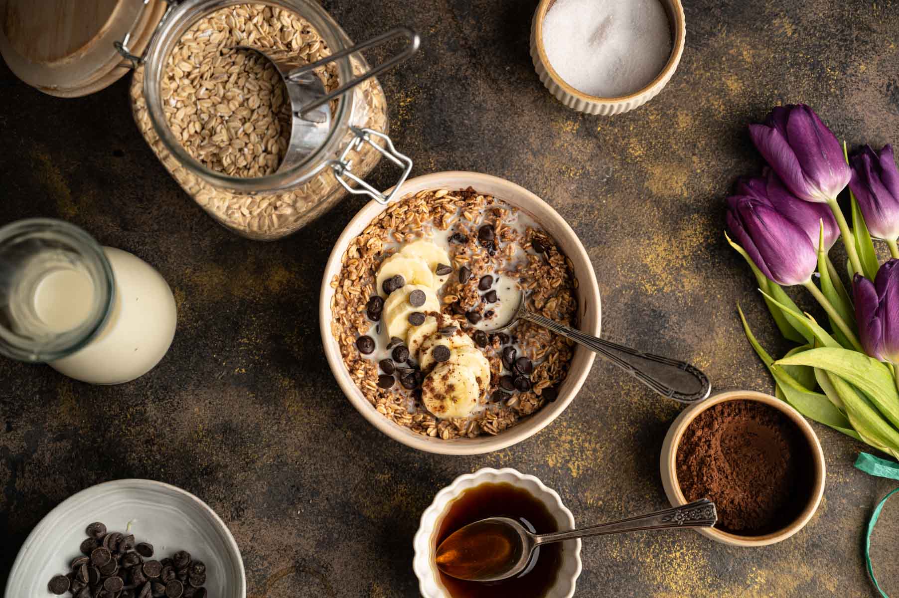 A bowl of oatmeal topped with banana slices, and chocolate chips.