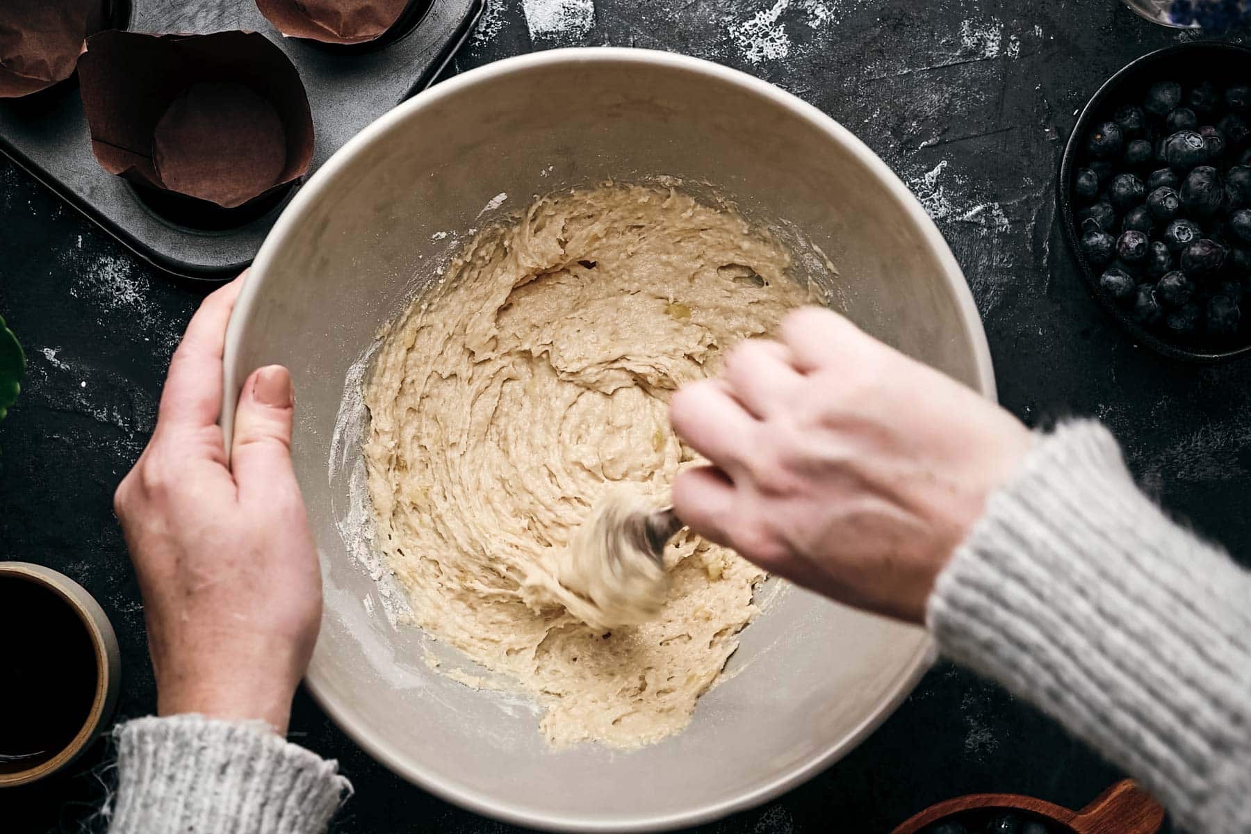 Close-up of a person stirring batter in a white mixing bowl.