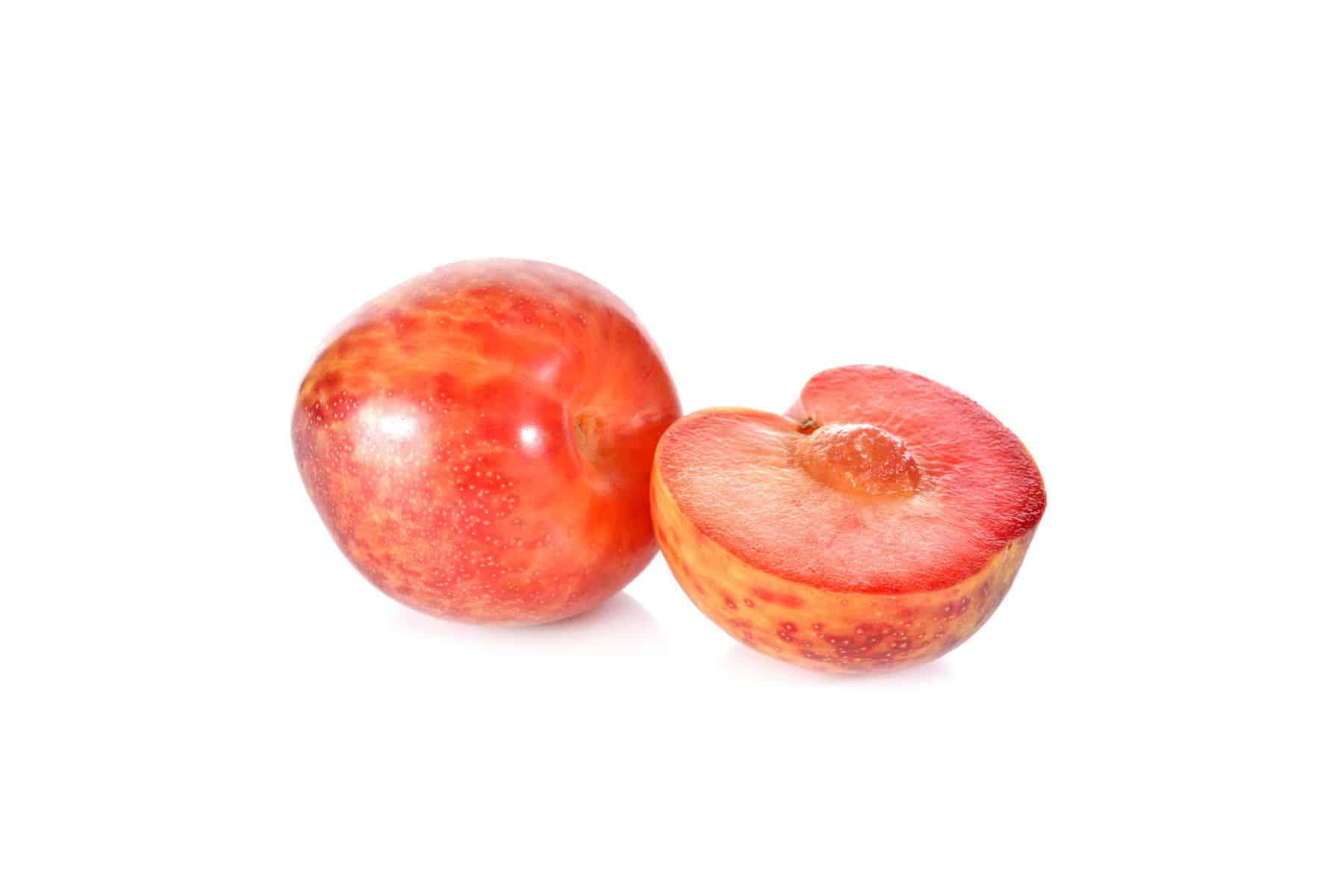 A whole and a halved red pluot on a white background.