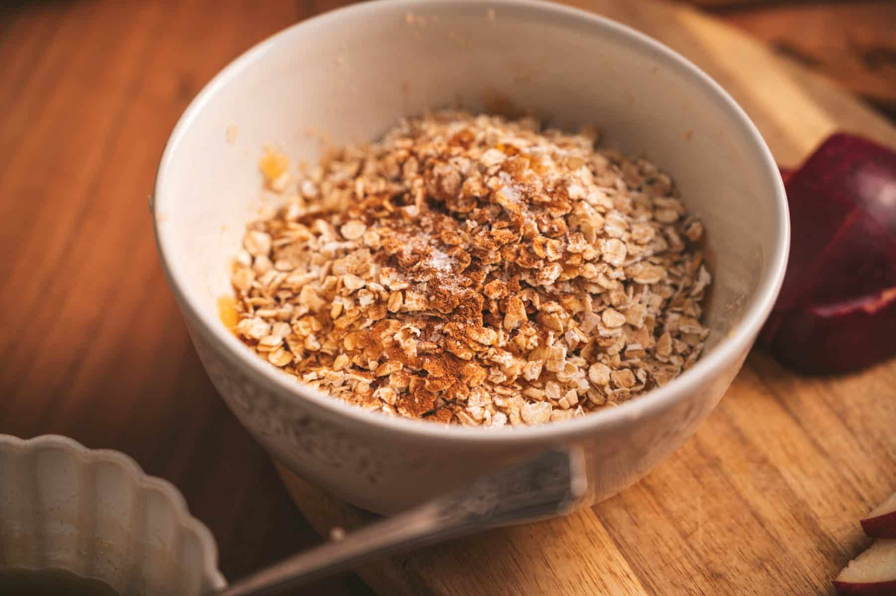 Oats, cinnamon, and maple syrup in a ceramic bowl.