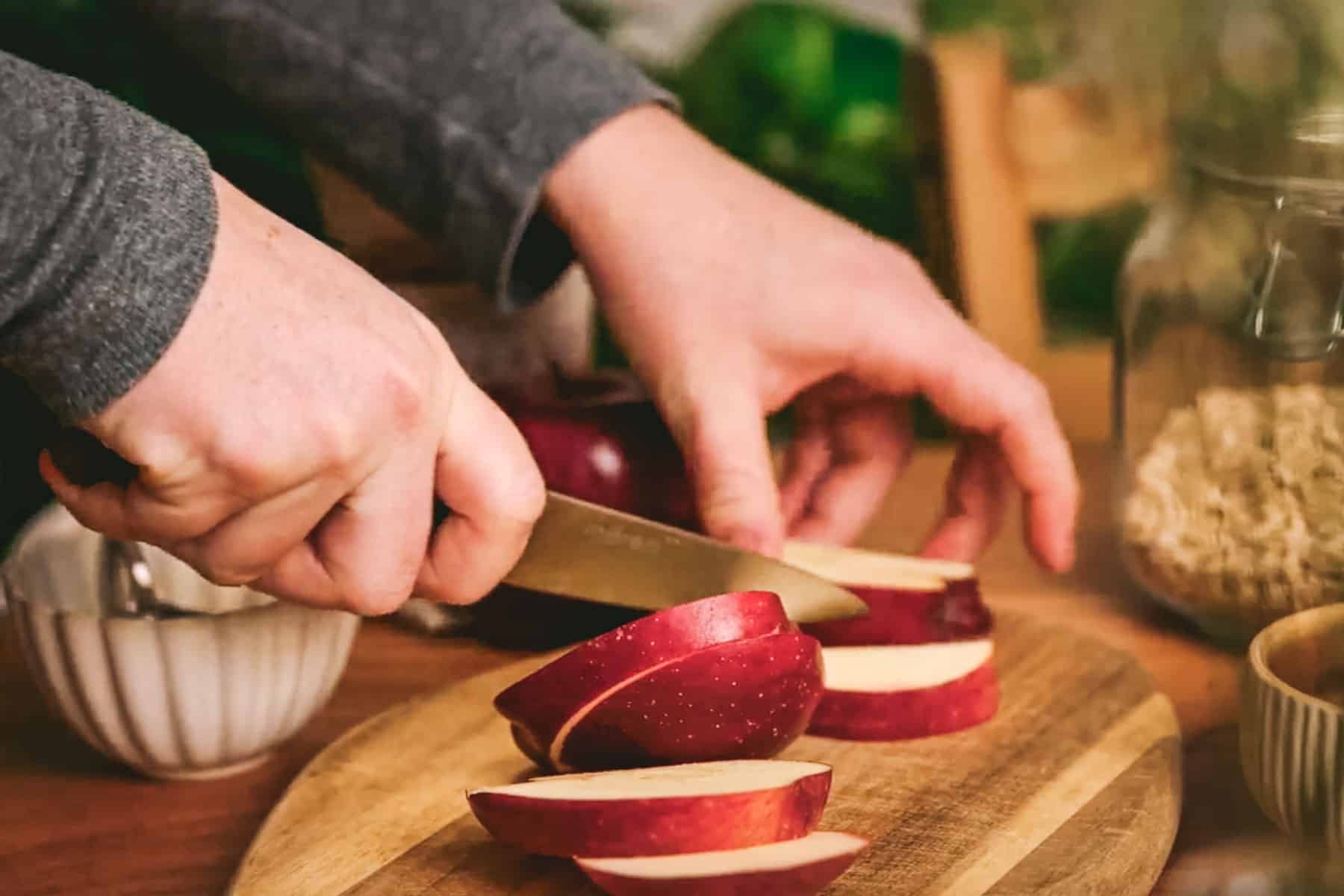 Person cutting apples on a cutting board.