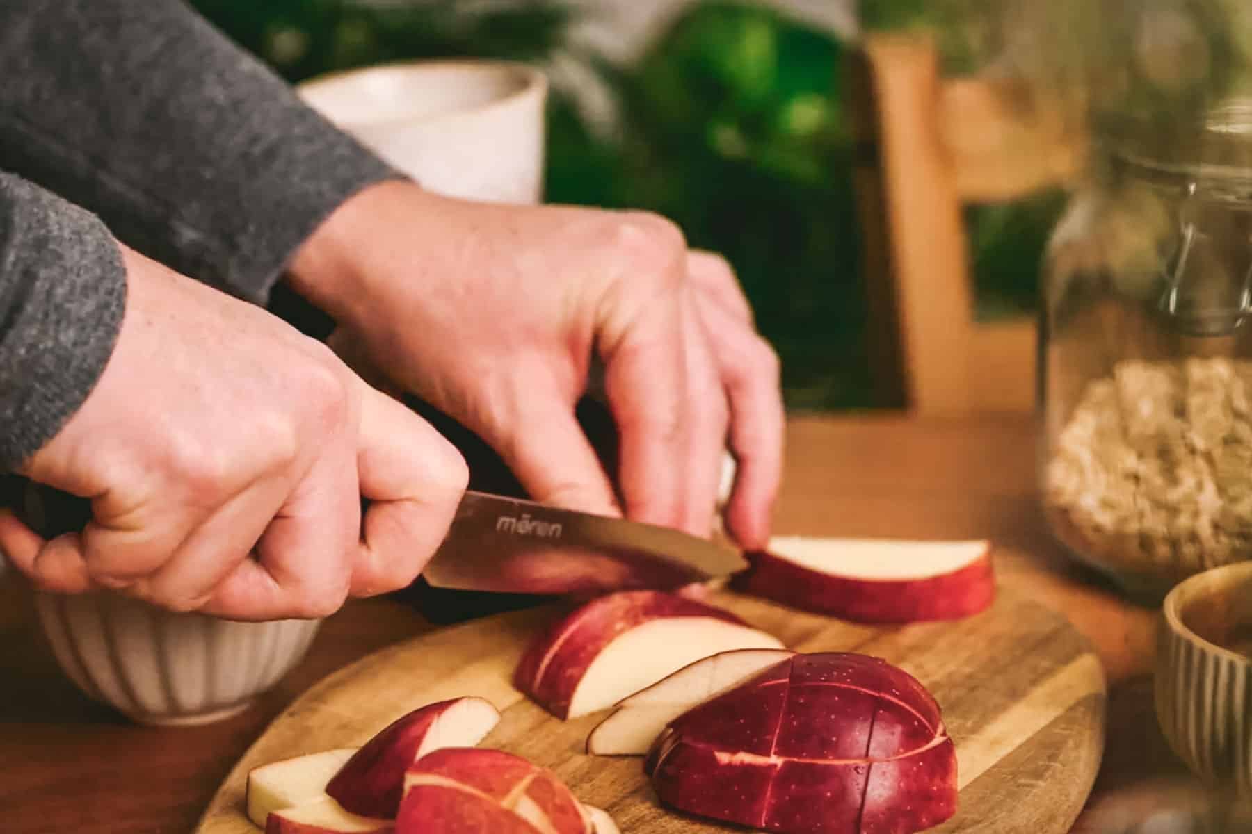 Woman thinly slicing apples on a cutting board.
