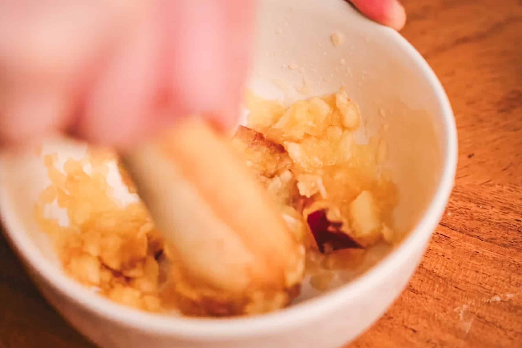 Muddling apples in a white bowl.