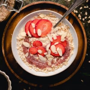 Bowl of single serve oatmeal for one with sliced strawberries on top.