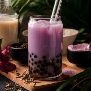 Glass of homemade taro bubble tea with a glass straw sticking out.