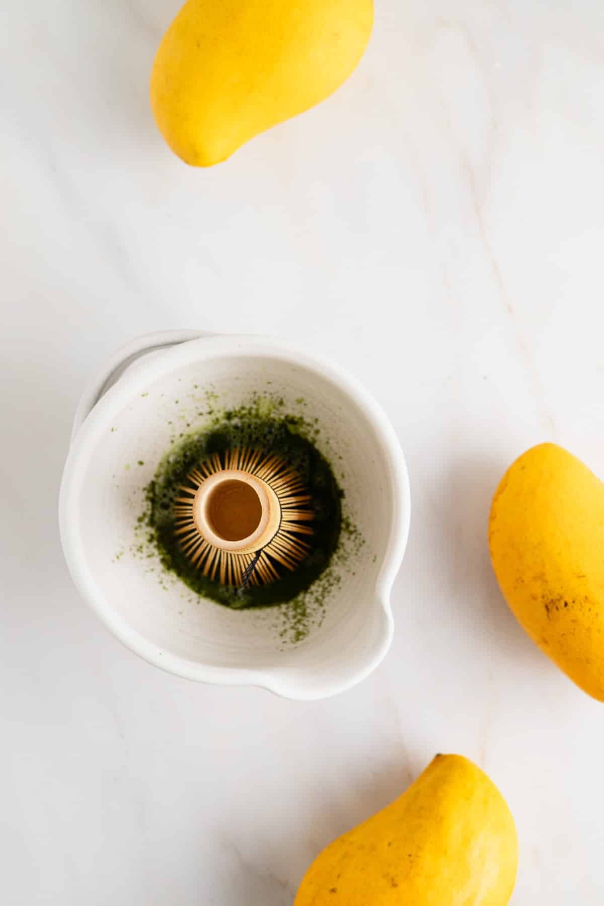 Mixing vibrant green matcha with hot water and a bamboo whisk.