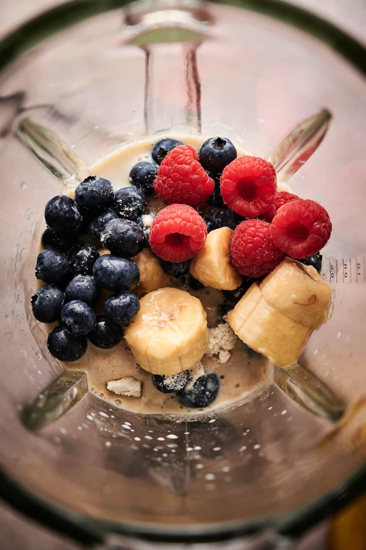 All the ingredients for a raspberry blueberry smoothie in a blender.