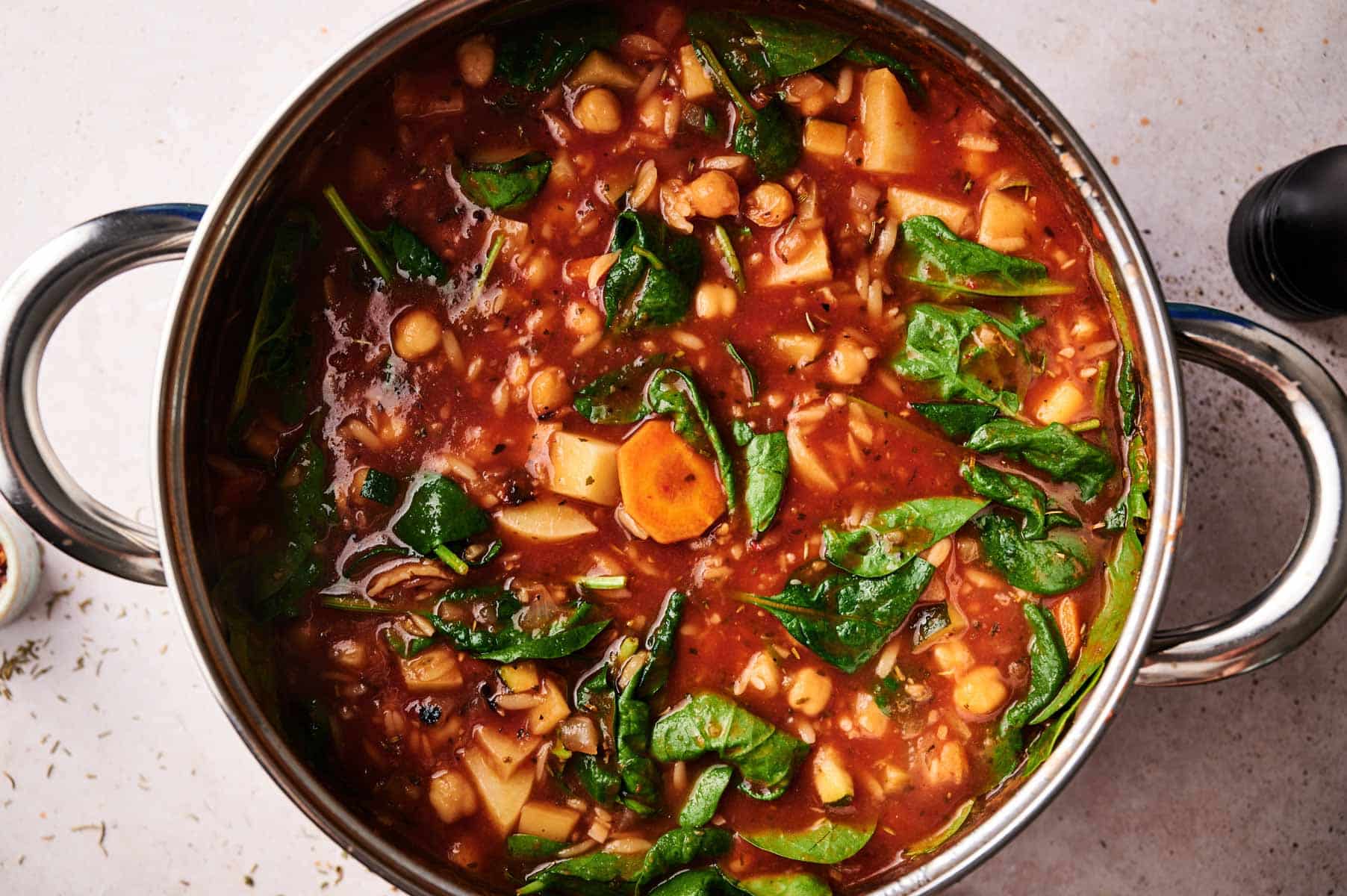 Orzo vegetable soup cooking in a stainless steel soup pot.