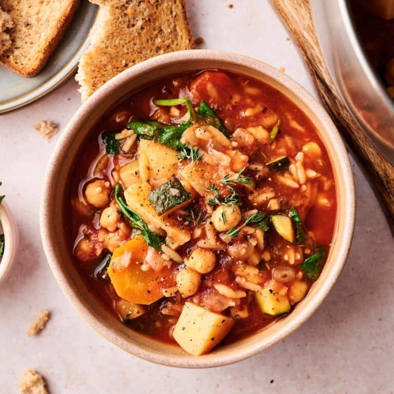 Orzo veggie soup in a bowl being served with toast.