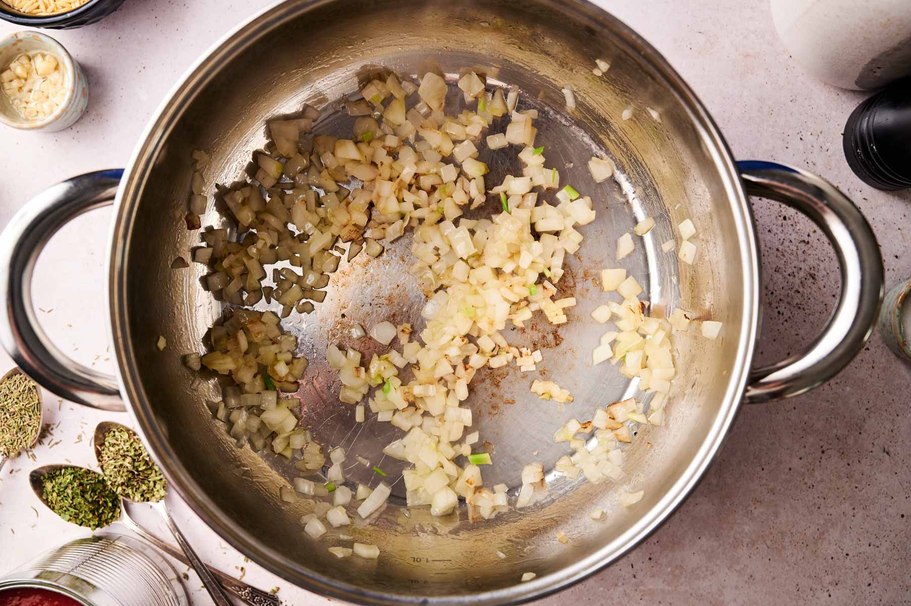Garlic and onion sauteeing in a stainless steel pot.