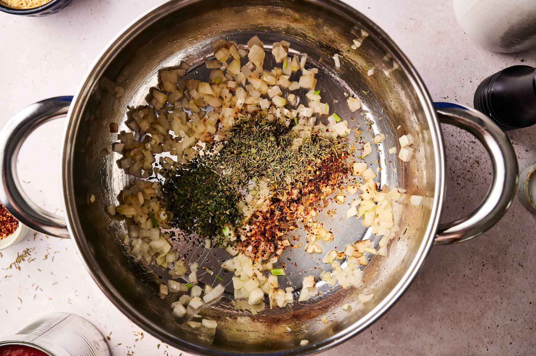 Onions, garlic, and spices sauteeing in stainless steel pot.