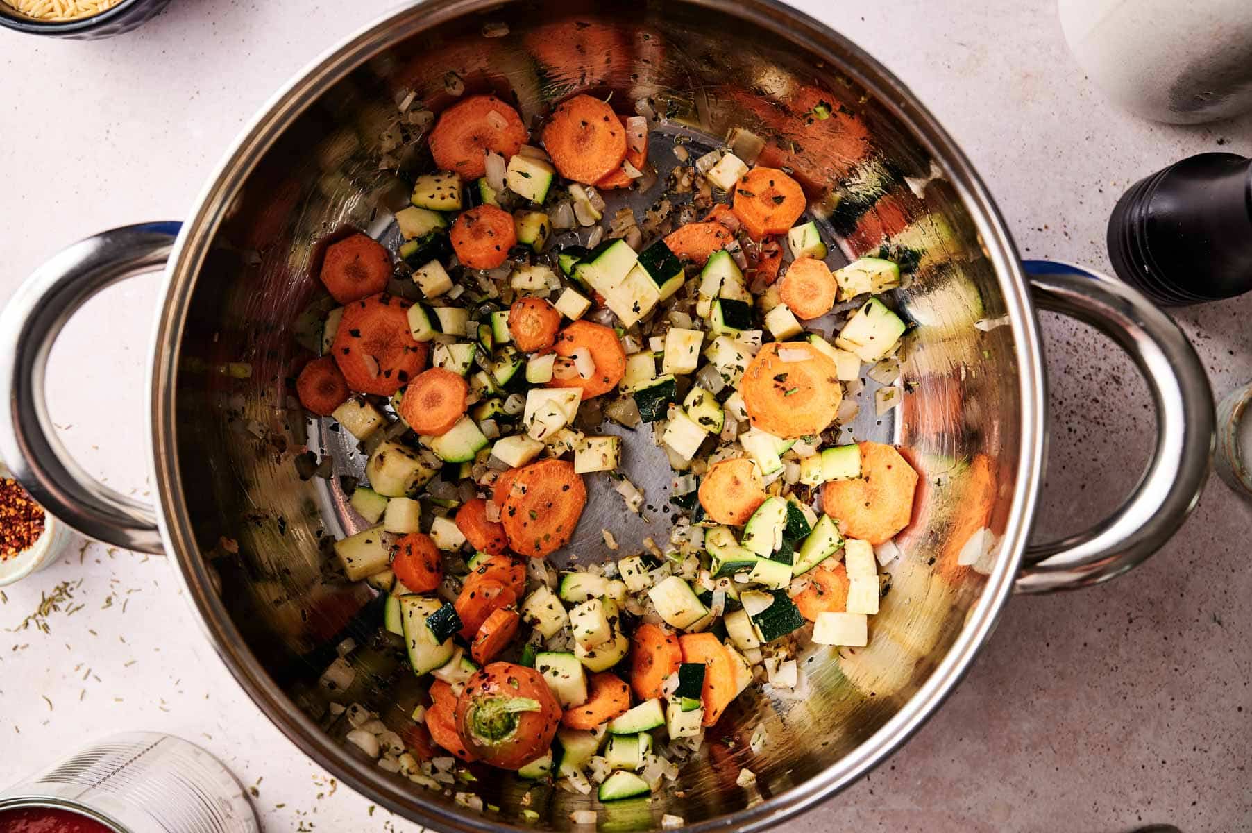 Veggies and spices sauteeing in stainless steel pot.