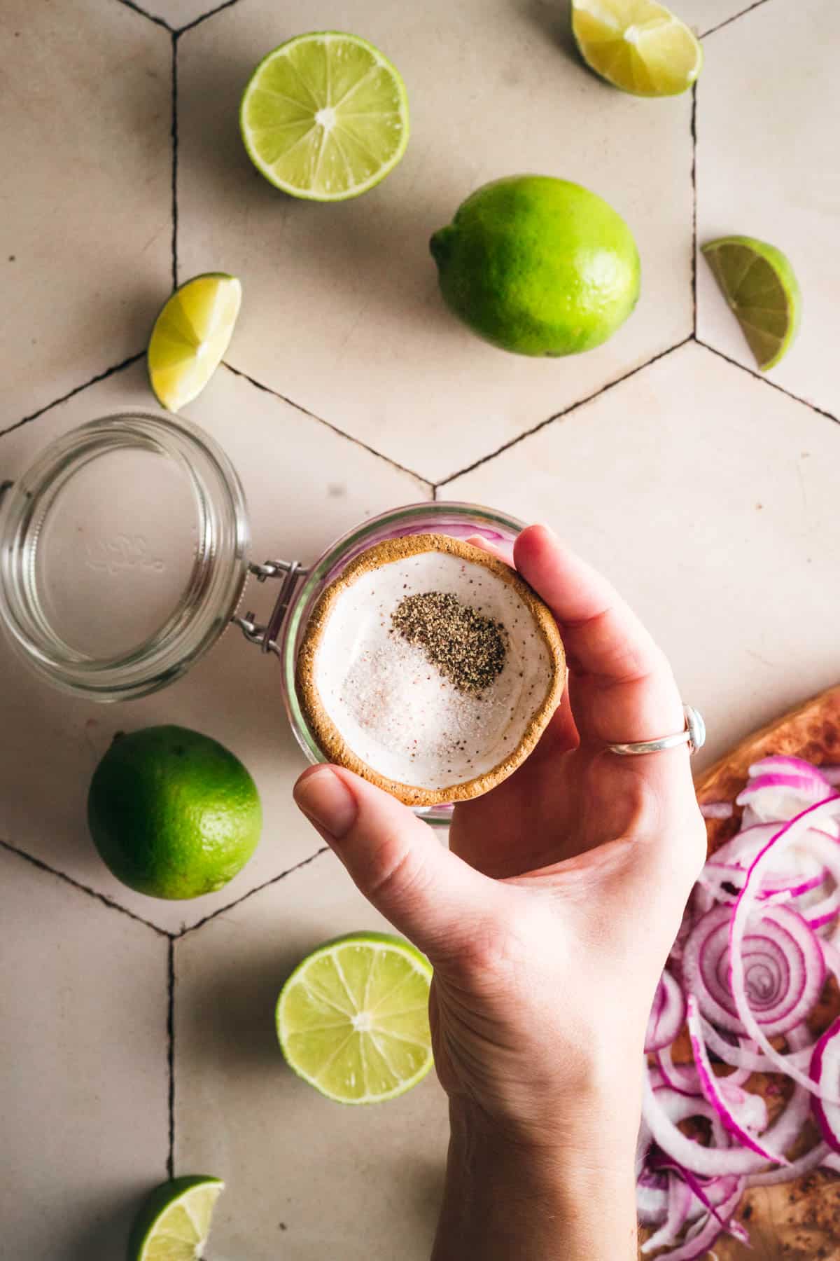 Salt and pepper being added to a glass jar.