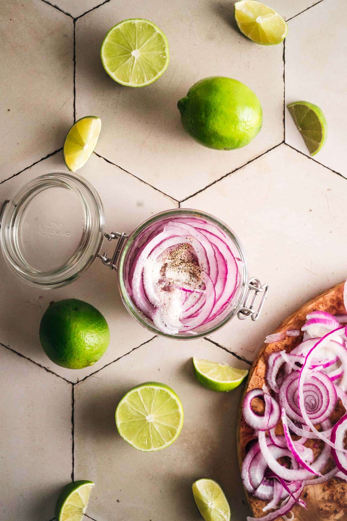 Red onion slices, salt, and pepper in a glass jar.