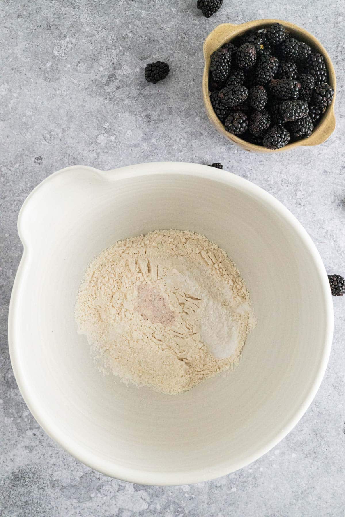 Dry ingredients for blackberry muffins added to a larger mixing bowl.