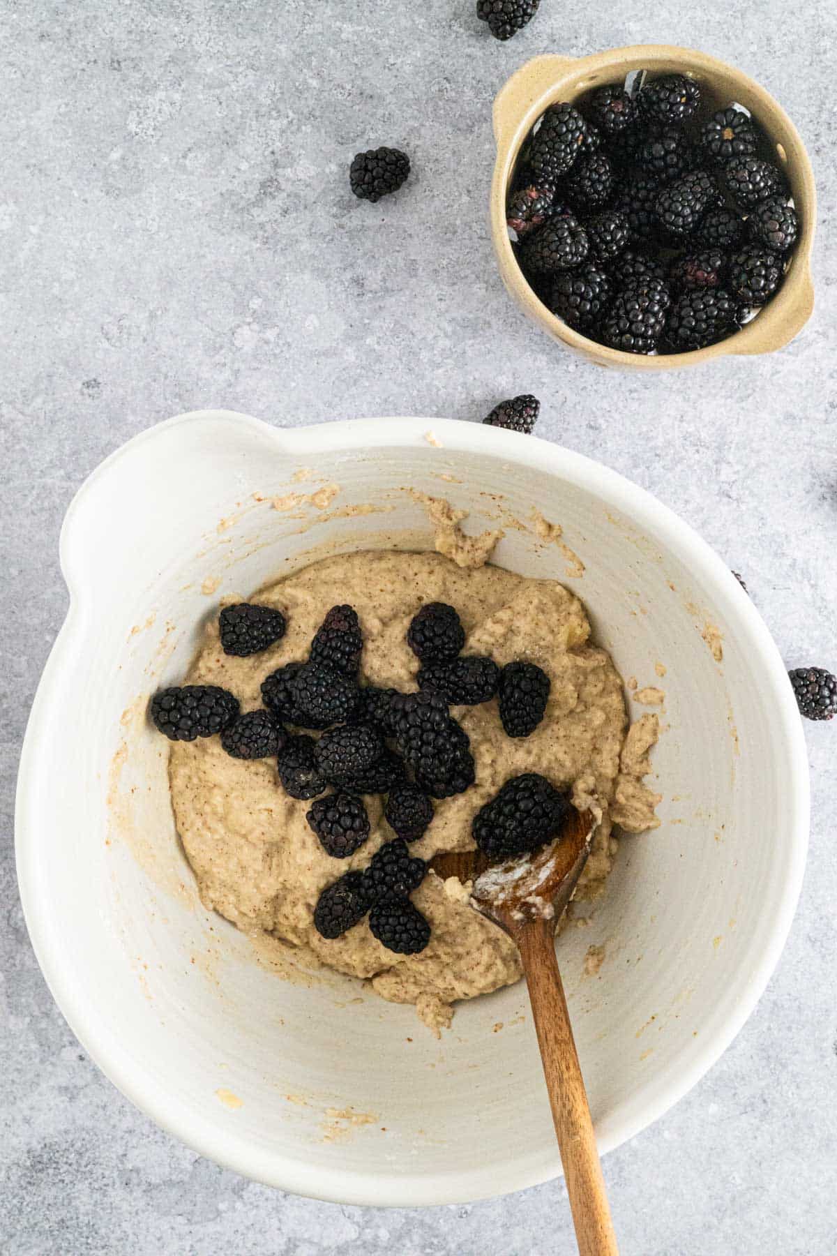 Adding and folding in blackberries to vegan muffin batter.