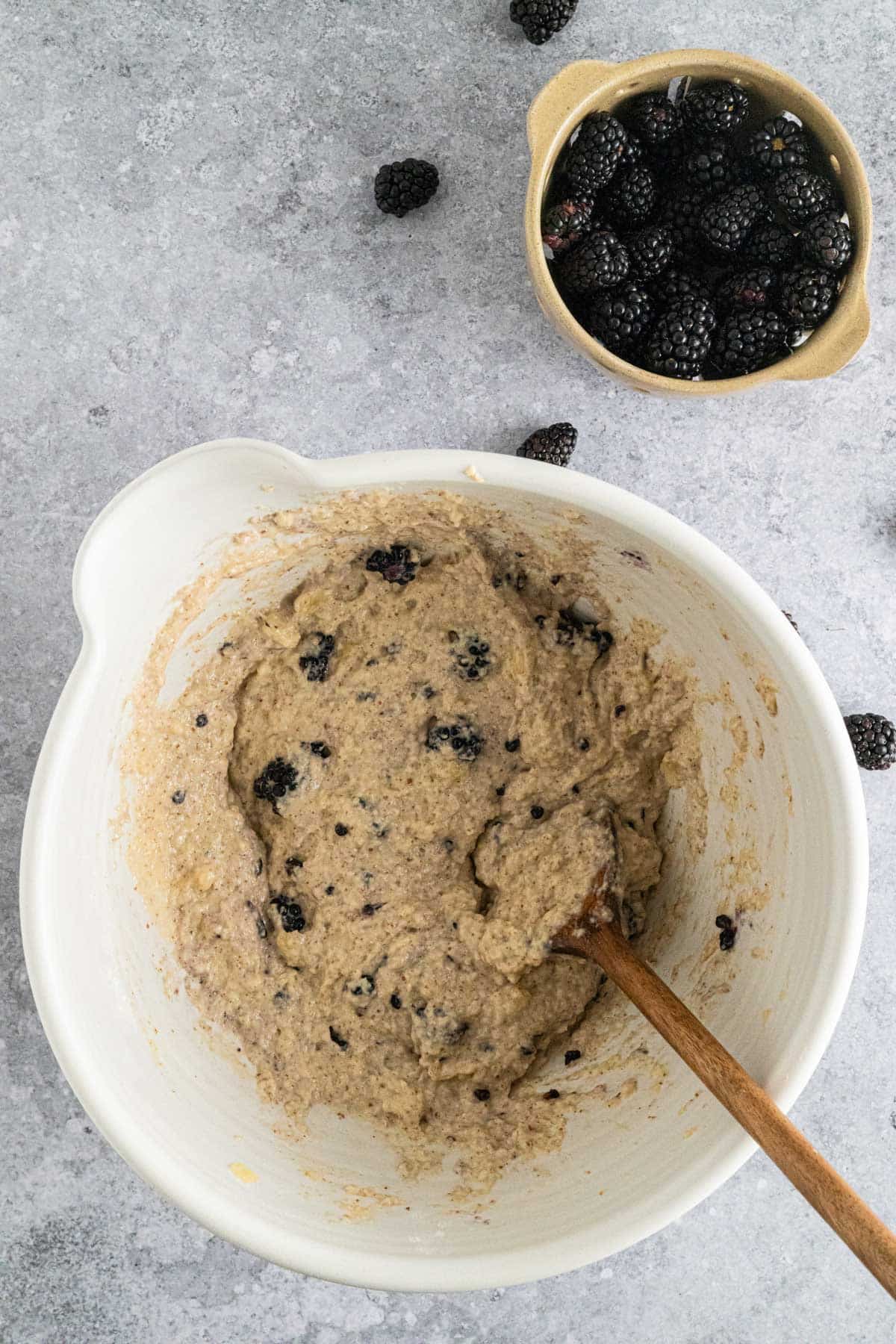 Adding and folding in blackberries to vegan muffin batter.
