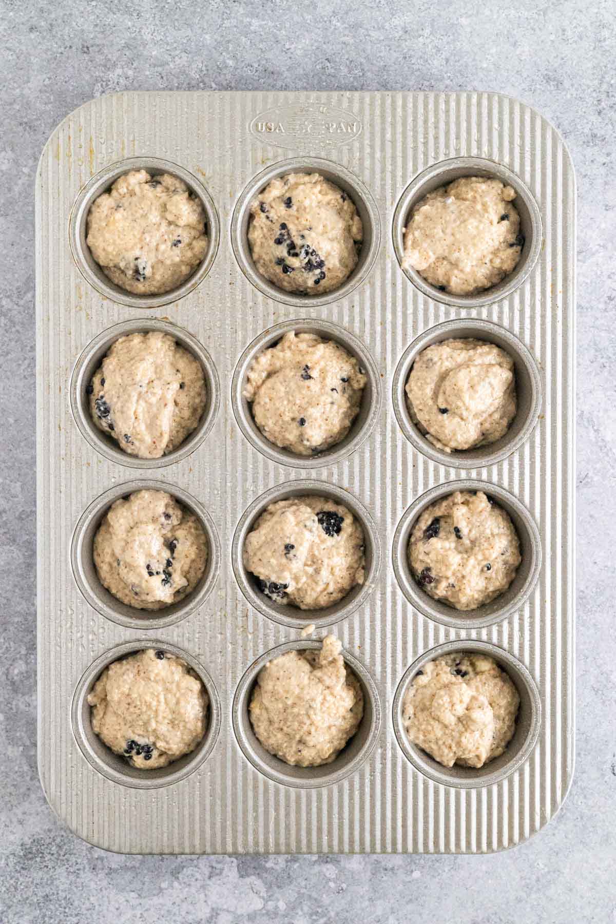 Scooped muffin batter into a muffin tray.