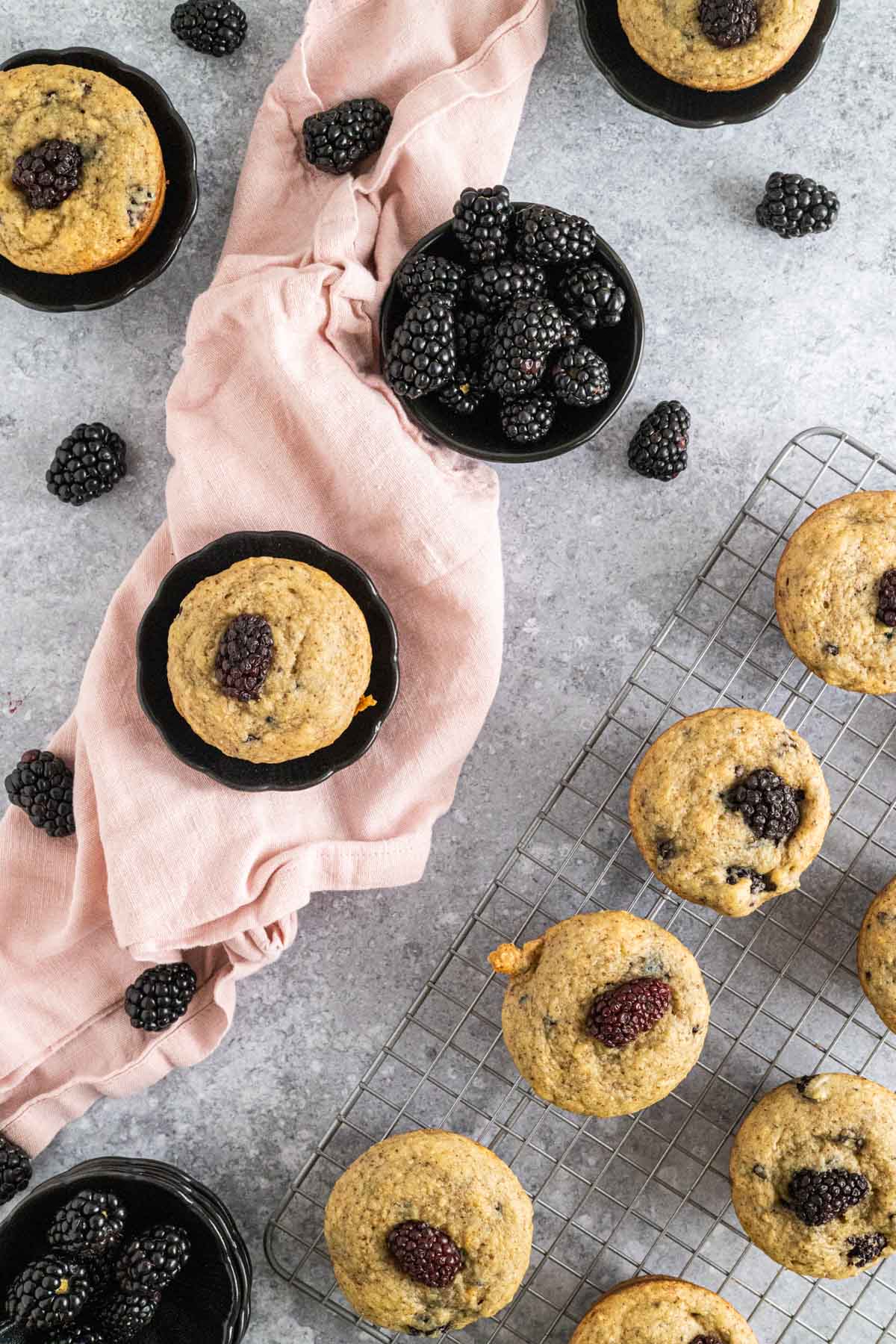 Homemade banana blackberry muffins on a gray stone counter.