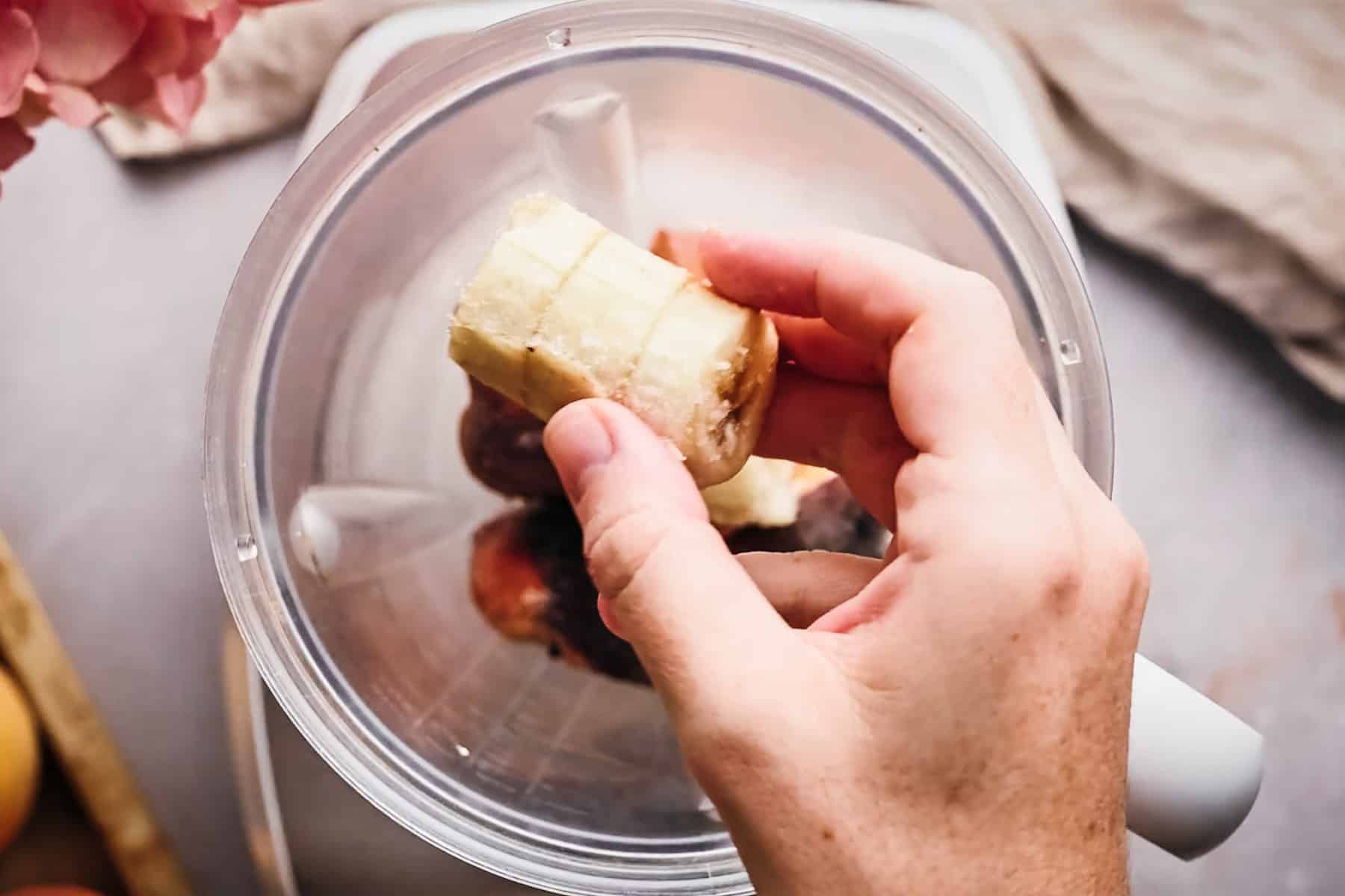 Adding frozen banana to a blender.
