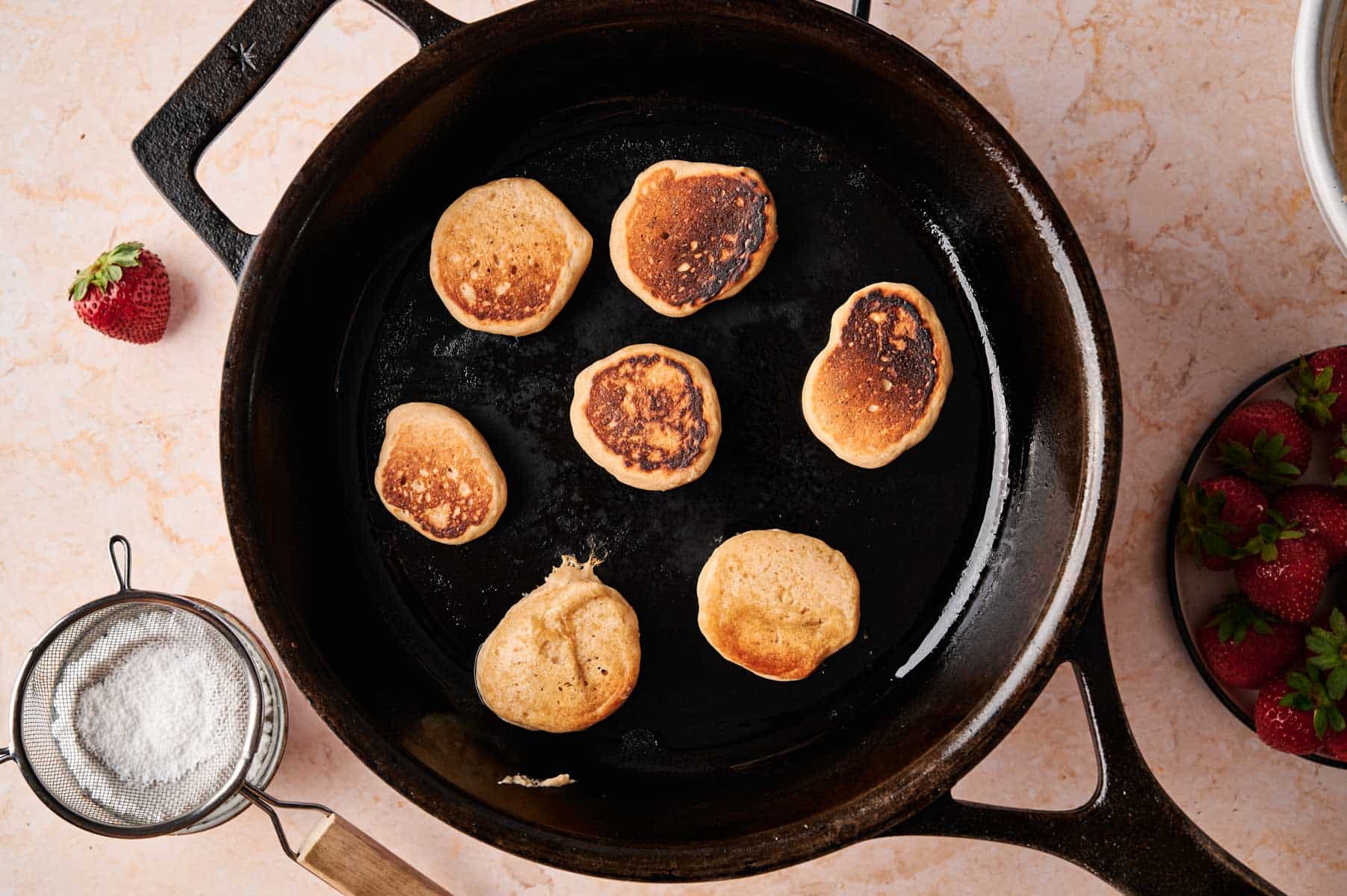 Cooking mini vegan pancakes in a cast iron skillet.